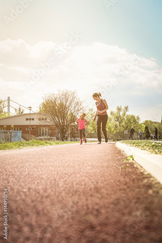 Caucasian mother and daughter jogging outdoors.