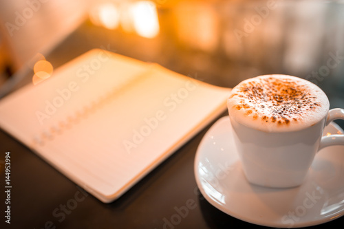 Cappuccino coffee and notebook on table in the morning