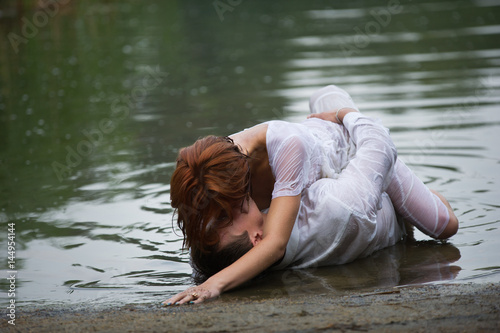 couple making love on the shore. Clothes are wet and the woman is laying on top of the man.
