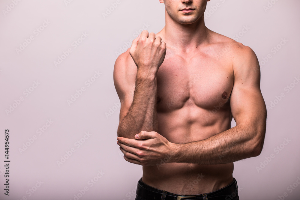 Fototapeta premium young man having pain in his elbow on grey background