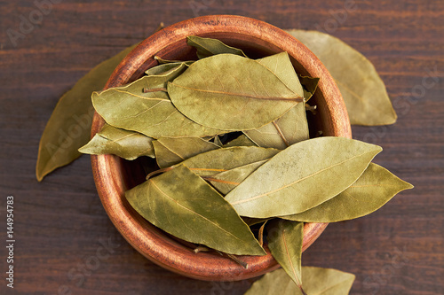 Dry bay leaves (Laurus nobilis) in wooden bowl. Top view