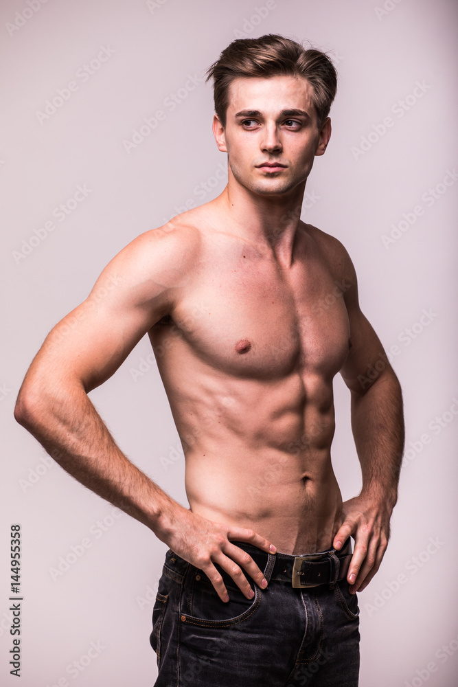 Healthy athlete muscular young man on a gray background