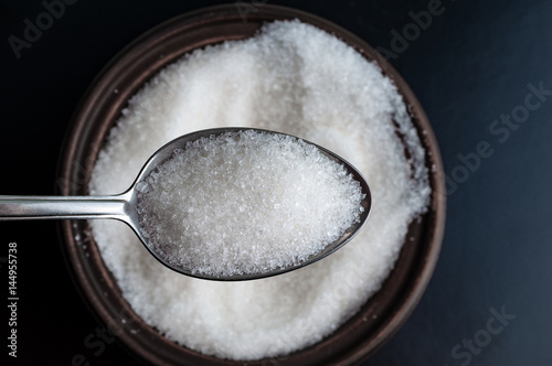 sugar in spoon over a bowl full of sugar