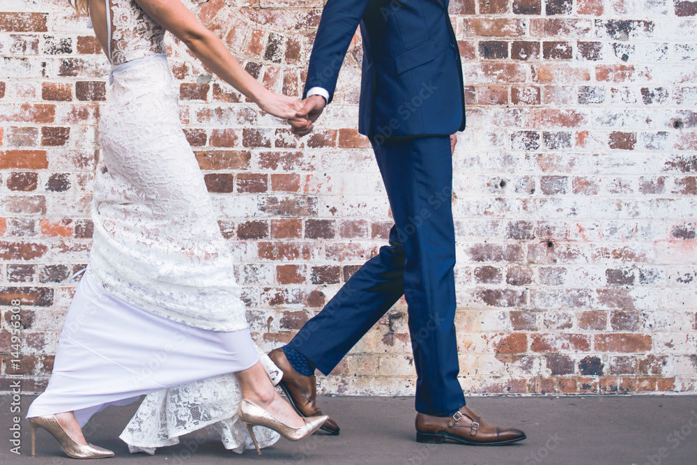 Wedding couple walking against brick wall Wedding couple walking against brick wall