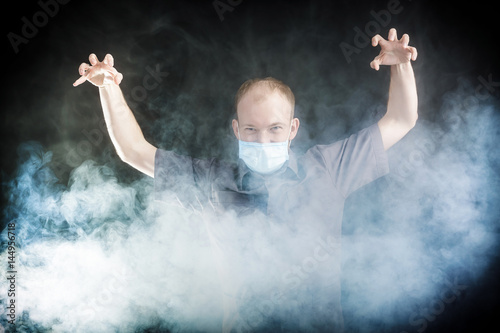 young doctor in a mask in smoke photo