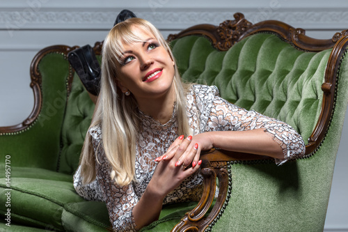 Beautiful blonde posing on green antique sofa