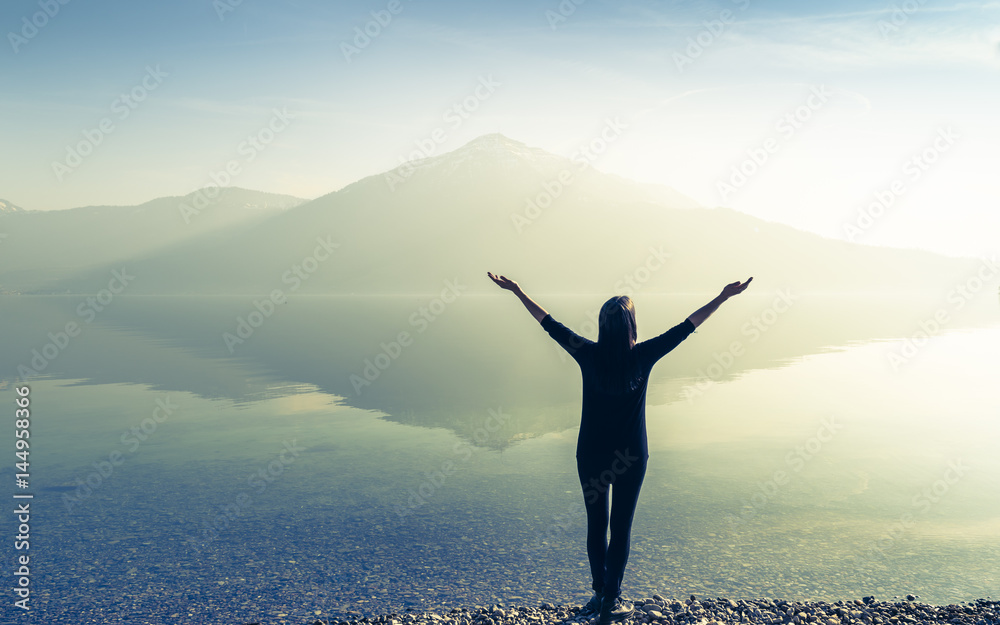 The joy of unity with nature. Woman with open arms by the lake on a  background of mountains. Photos | Adobe Stock