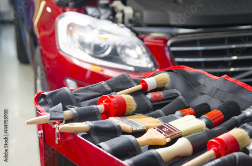Complect of brushes for cleaning car detailing in front of red car