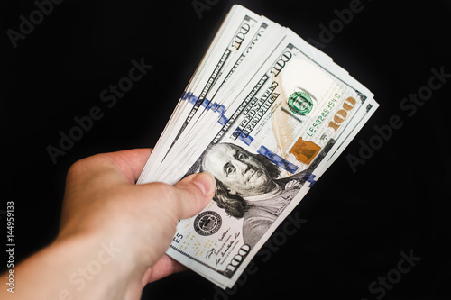 Hand with dollar bills on a black background

