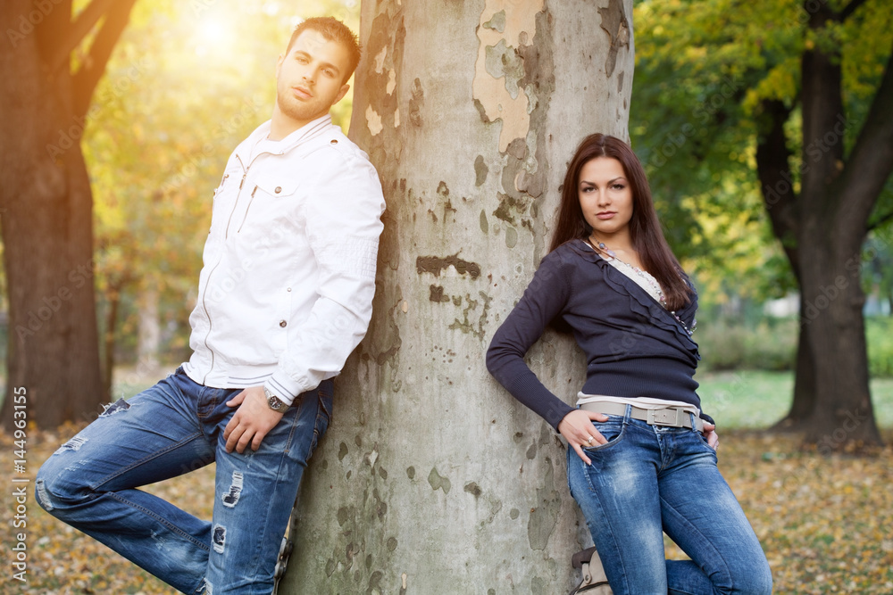 Stylish young couple standing by the tree.