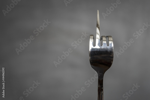 Fotografie Fork bent in the form of an obscene gesture sign of the middle finger on a blurr