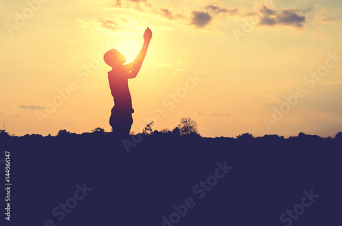 Silhouette of man pray with sunset background