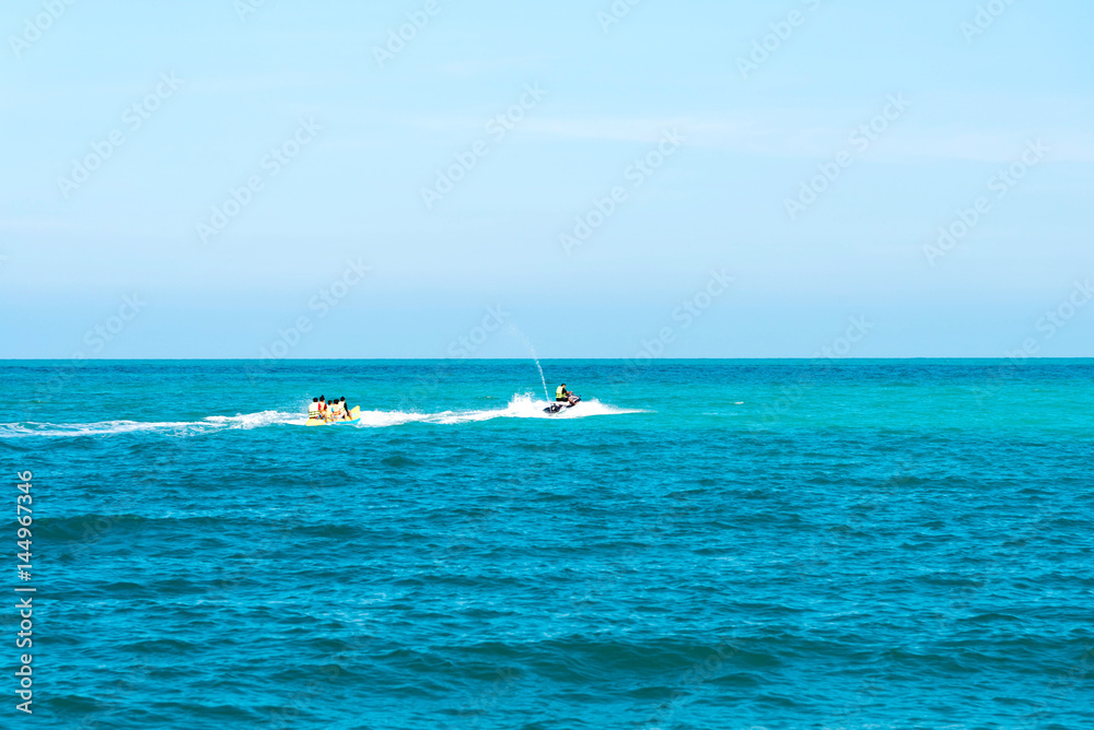 summer holiday by the sea. Beautiful bright blue water and red and white boat and yellow banana boat.