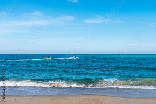 summer holiday by the sea. Beautiful bright blue water and red and white boat and yellow banana boat.