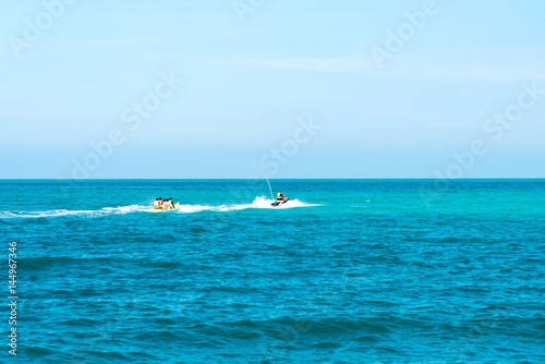 summer holiday by the sea. Beautiful bright blue water and red and white boat and yellow banana boat. © somchaichoosiri