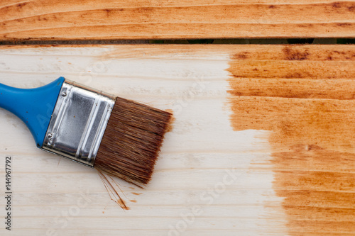 Paintbrush on the fresh painted wooden planks board