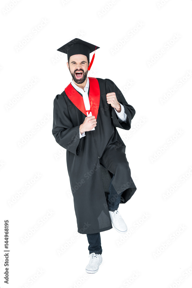 Excited young man in graduation hat holding diploma and triumphing on white Excited young man in graduation hat holding diploma and triumphing on white