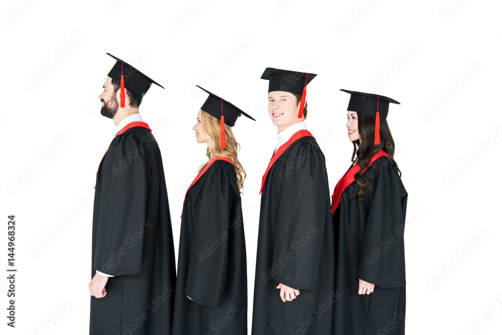 Smiling students in graduation caps standing in a row isolated on white Smiling students in graduation caps standing in a row isolated on white