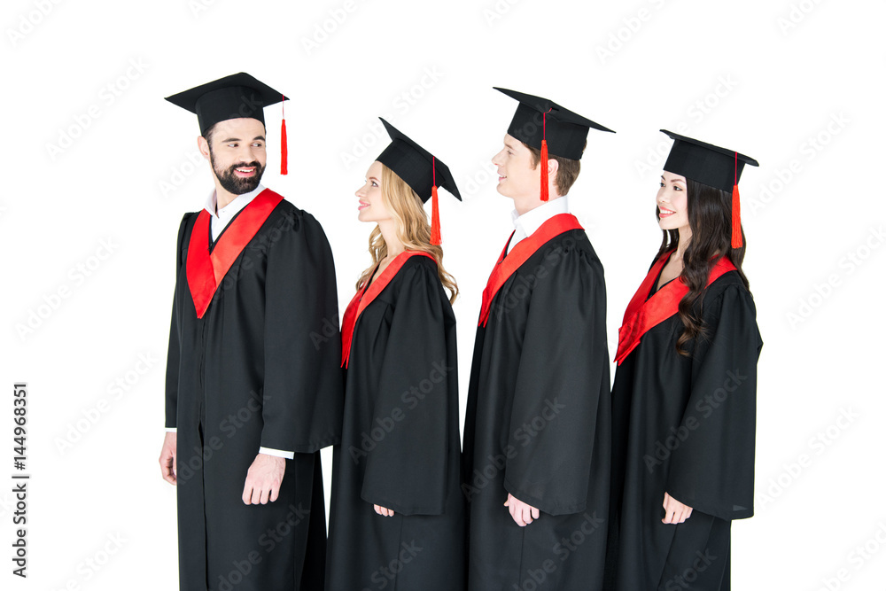 Smiling students in graduation caps standing in a row isolated on white Smiling students in graduation caps standing in a row isolated on white