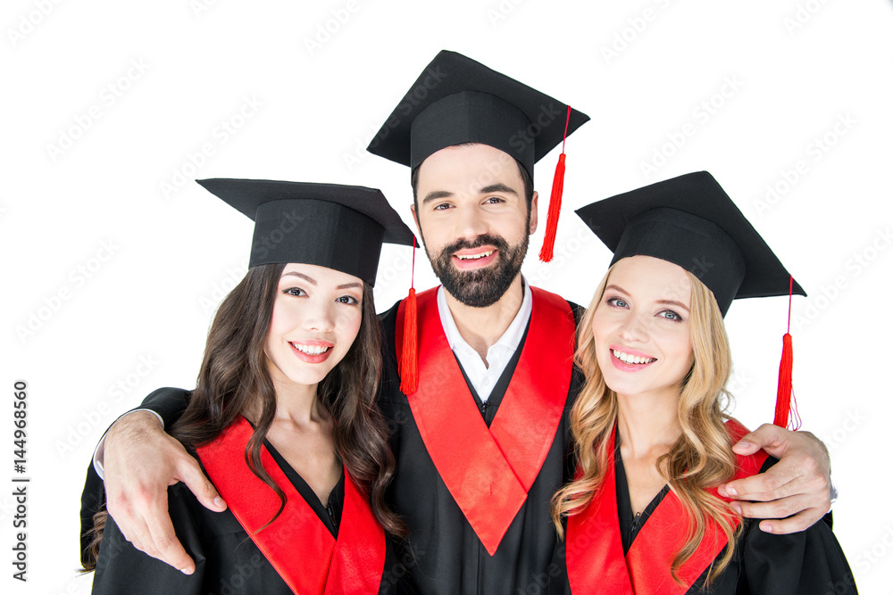 Happy students in academic caps standing embracing and smiling at camera Happy students in academic caps standing embracing and smiling at camera
