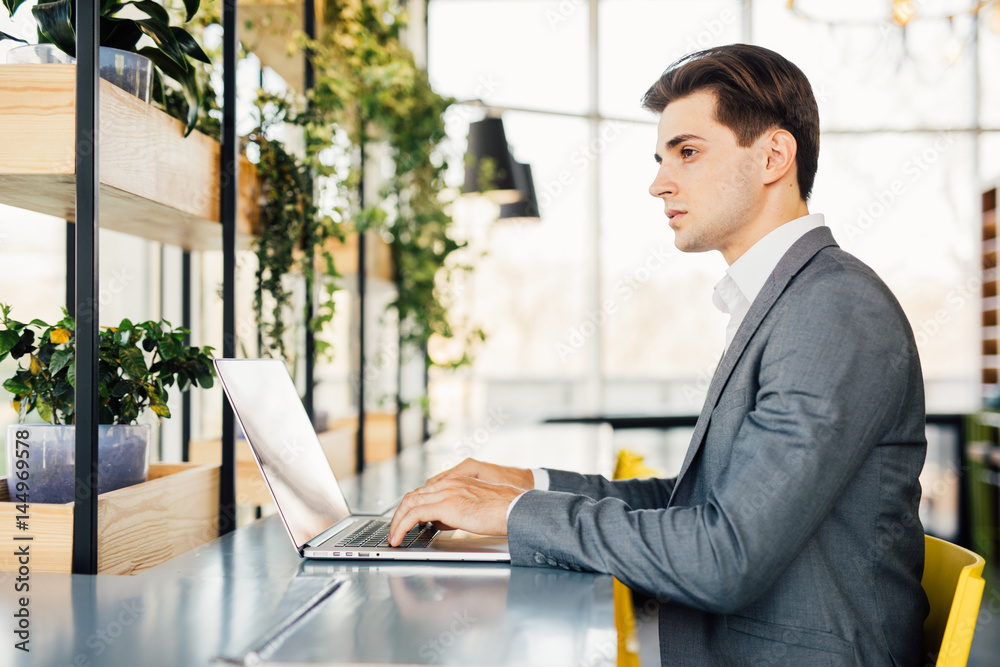Side view of business man sitting by the table with laptop computer