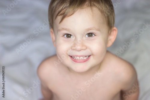 Portrait of a cute little happy boy. Babe fools around in bed.