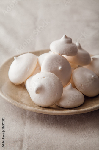 Homemade meringues on ceramic plate and linen fabric