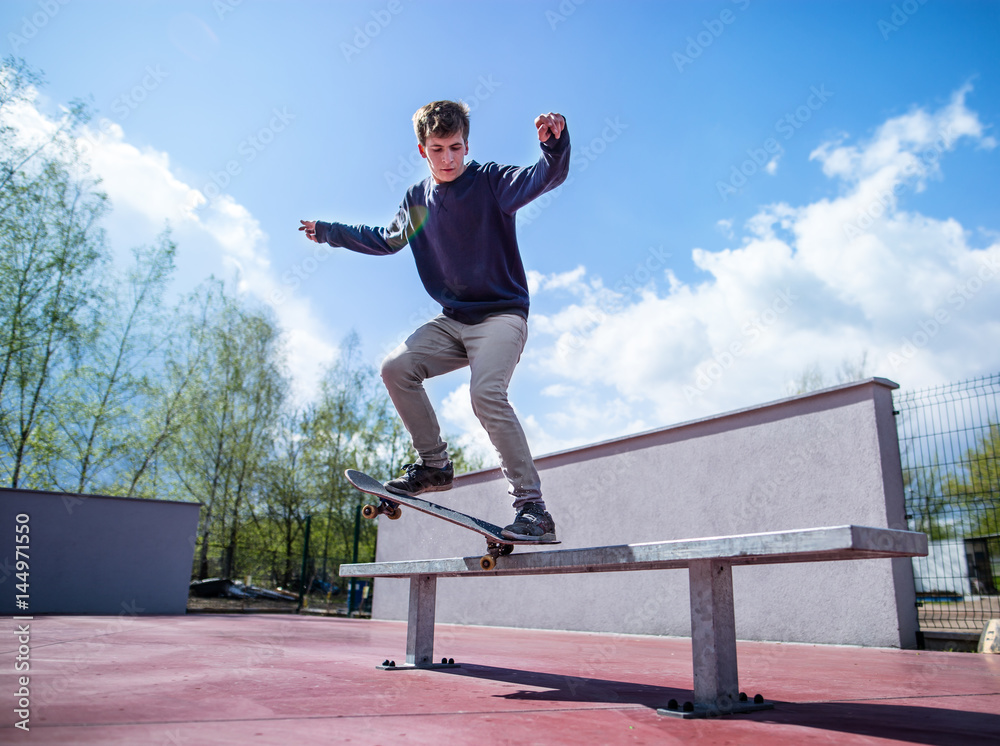 Skater doing croocked grind trick on bench in skatepark Photos | Adobe Stock