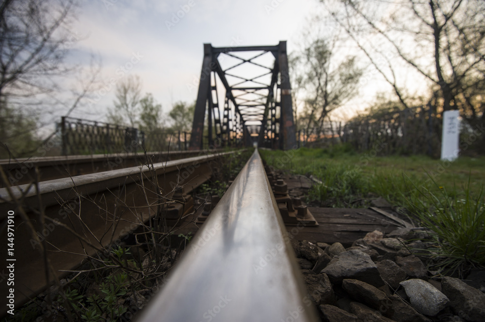 Railway metallic bridge and its reflection in one of the tracks Railway metallic bridge and its reflection in one of the tracks