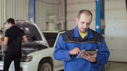 car mechanic using tablet touch screen on a car cepair service photo