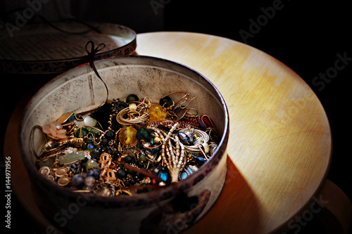 Variety of women's earrrings in a round metal box photo