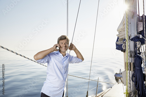 Portrait of smiling mature man on the phone on his sailing boat