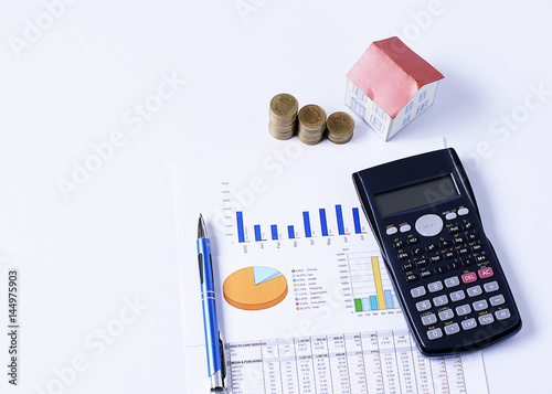 Mortgage loans concept with House paper and coins stack with pen and calculator on business chart