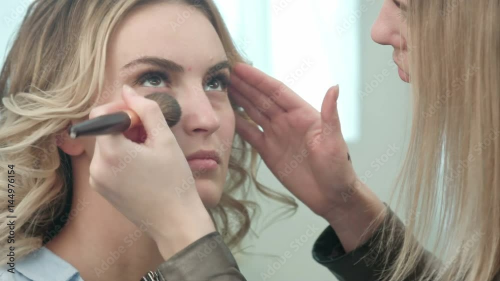 Professional make up artist applying powder to a young model face Professional make up artist applying powder to a young model face