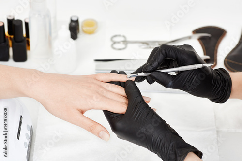 Woman receiving  manicure procedure at nail salon. Beauty care.