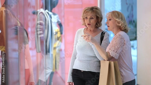 Excited women looking at clothes in store window photo