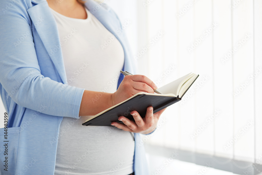 Young pregnant woman writes to her diary