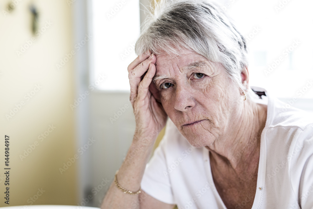 Mature woman at home touching her head with her hands while having a headache pain Mature woman at home touching her head with her hands while having a headache pain