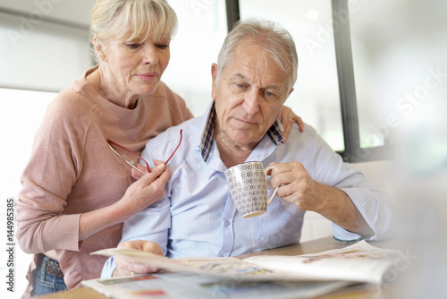 Senior couple reading newspaper together at home
