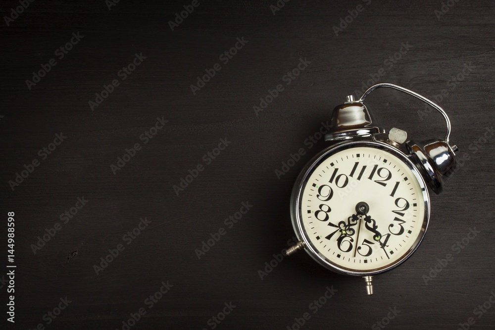 Retro metal alarm clock on a black wooden background. Open your eyes. Reveille to wake up. Place for text.