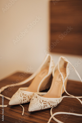 bouquet of flowers and greenery and shoes bride and groom lying on an old wooden bench