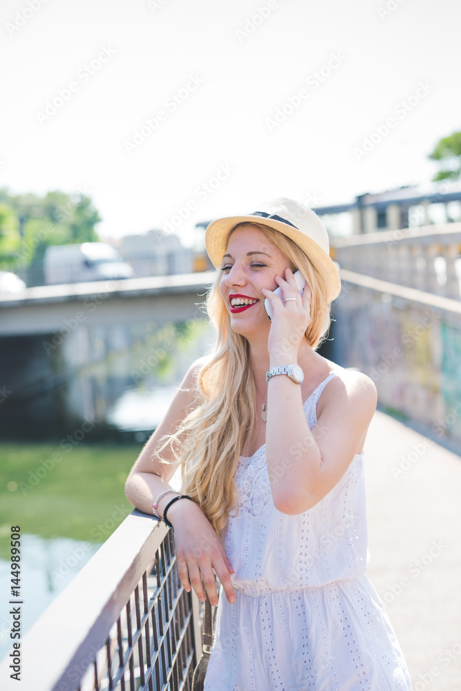 Young beautiful woman outdoor city back light talking smart phone laughing - communication, call, happiness concept Young beautiful woman outdoor city back light talking smart phone laughing - communication, call, happiness concept