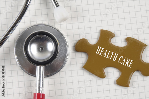 Medical concept with stethoscope,piece of puzzle and coins with HEALTH CARE conceptual text. photo