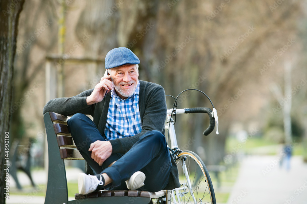 Obraz premium Senior man with bicycle and smart phone, making phone call