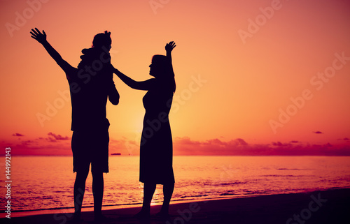 happy family with little child on sunset beach