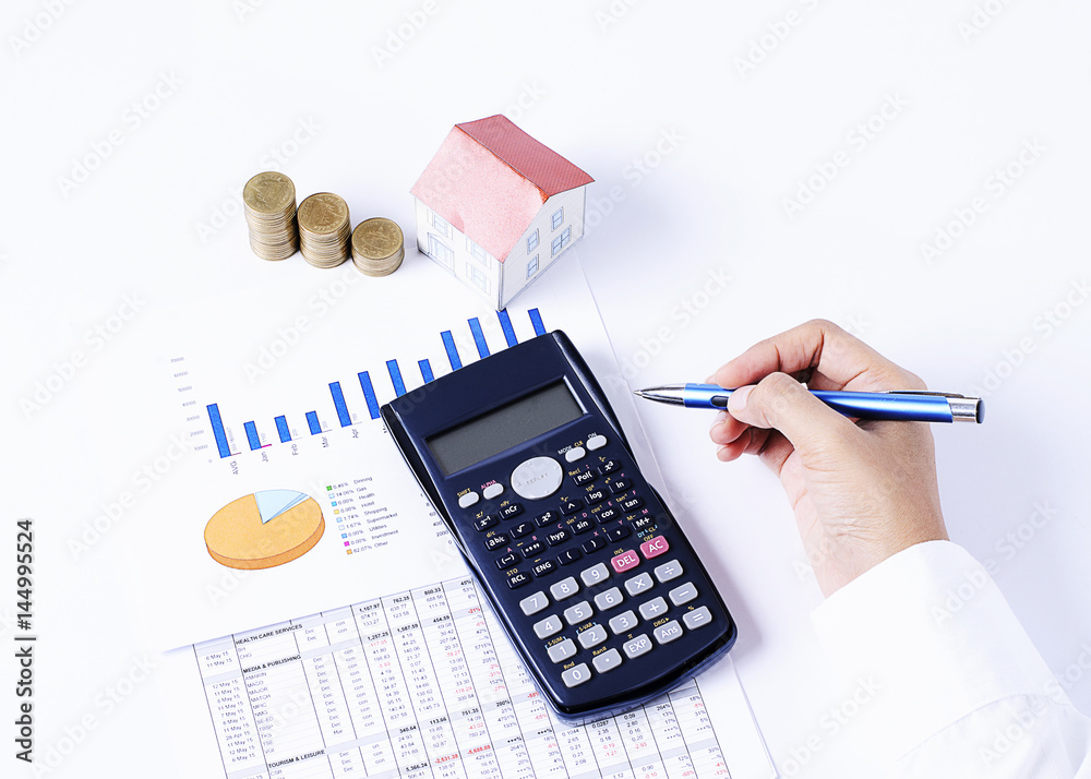 Hand holding pen and calculator and house paper and coins stack and business chart Hand holding pen and calculator and house paper and coins stack and business chart