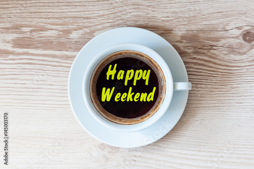 White cup of coffee on wooden table with note HAPPY WEEKEND. Top view, holiday concept photo