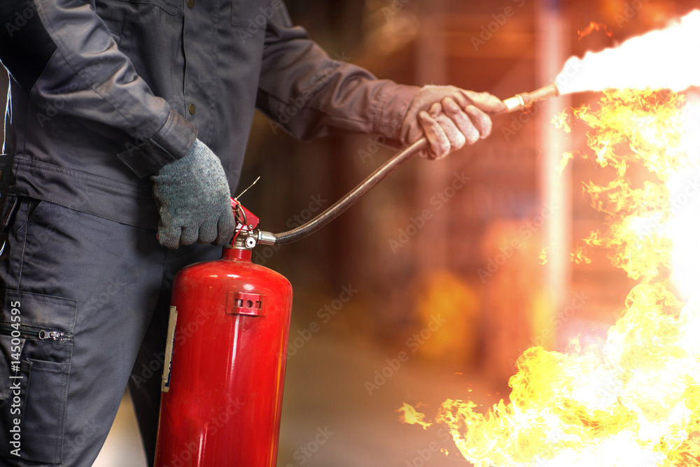 Naklejka premium Man using fire extinguisher fighting fire closeup photo.