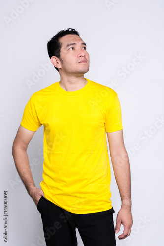 Handsome bearded man in a blank yellow t-shirt  on white background. © 2p2play
