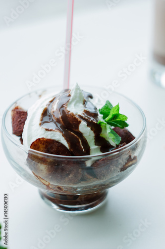 Nice banana and chocolate dessert in a glass bowl on white table.